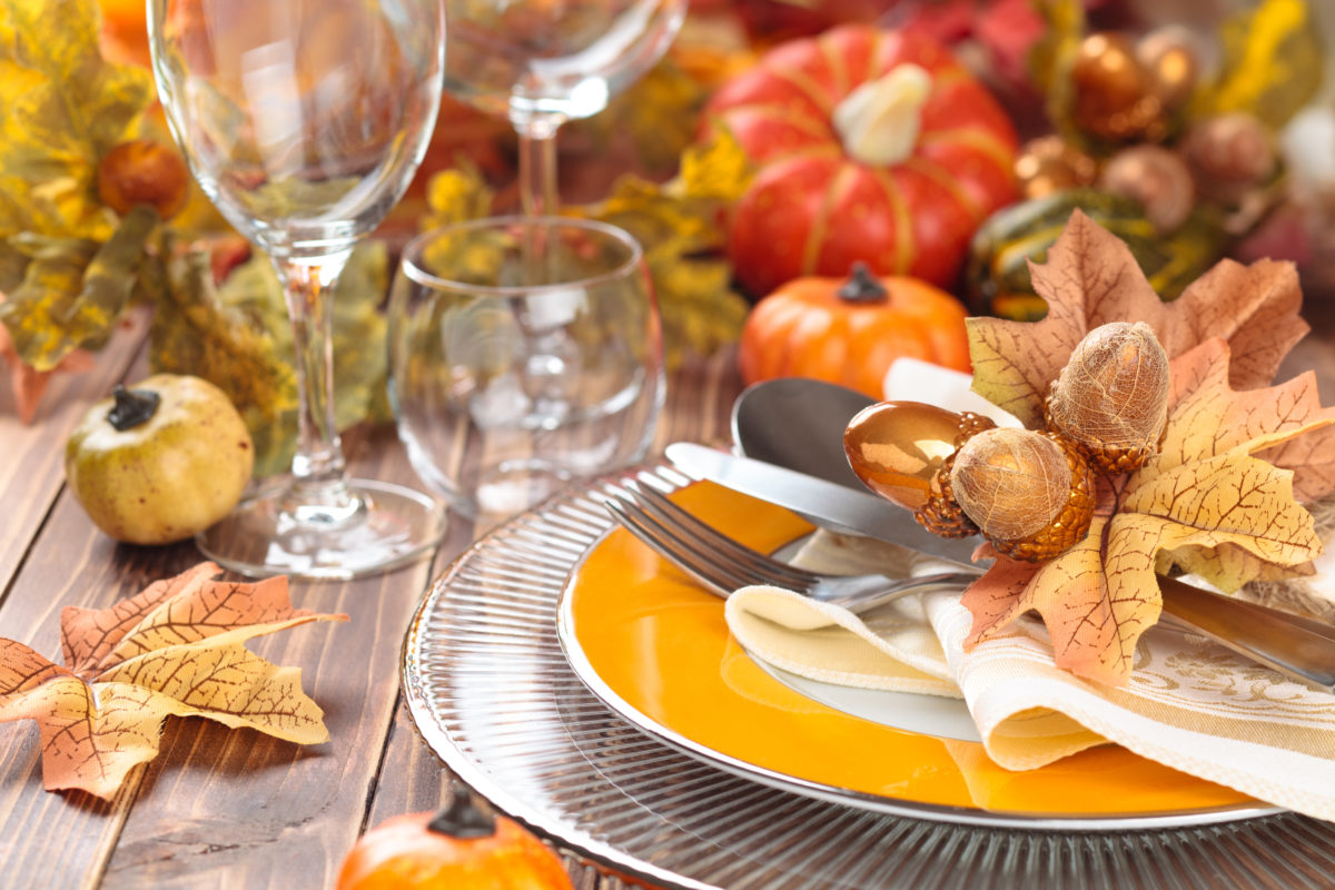 Autumn place setting with leaves, candles and pumpkins.