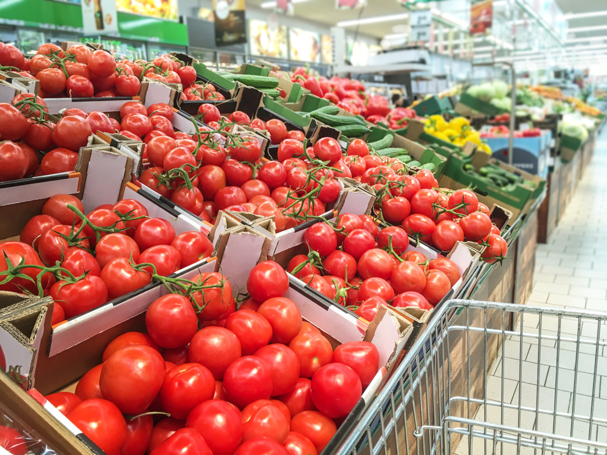 Variety of fresh vegetables for sale in the supermarket and empty shopping cart