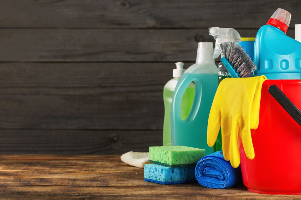 Basket with variety cleaning product on wooden table with copy space