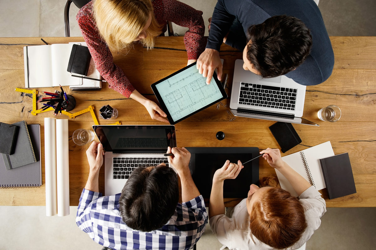 High angle view of team of architecs designing layout on laptop. Architect showing project house at his colleague and working together on laptop. Top view of business people in a meeting.