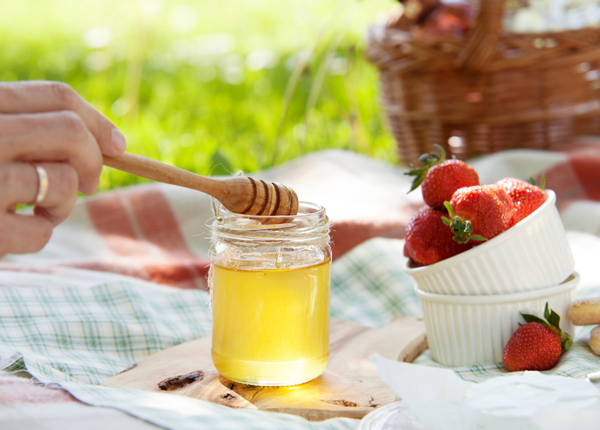 Honey and fresh strawberry served for summer picnic