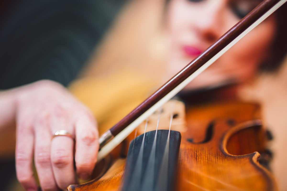 Beautiful woman artist playing the violin on the stage. Close up.