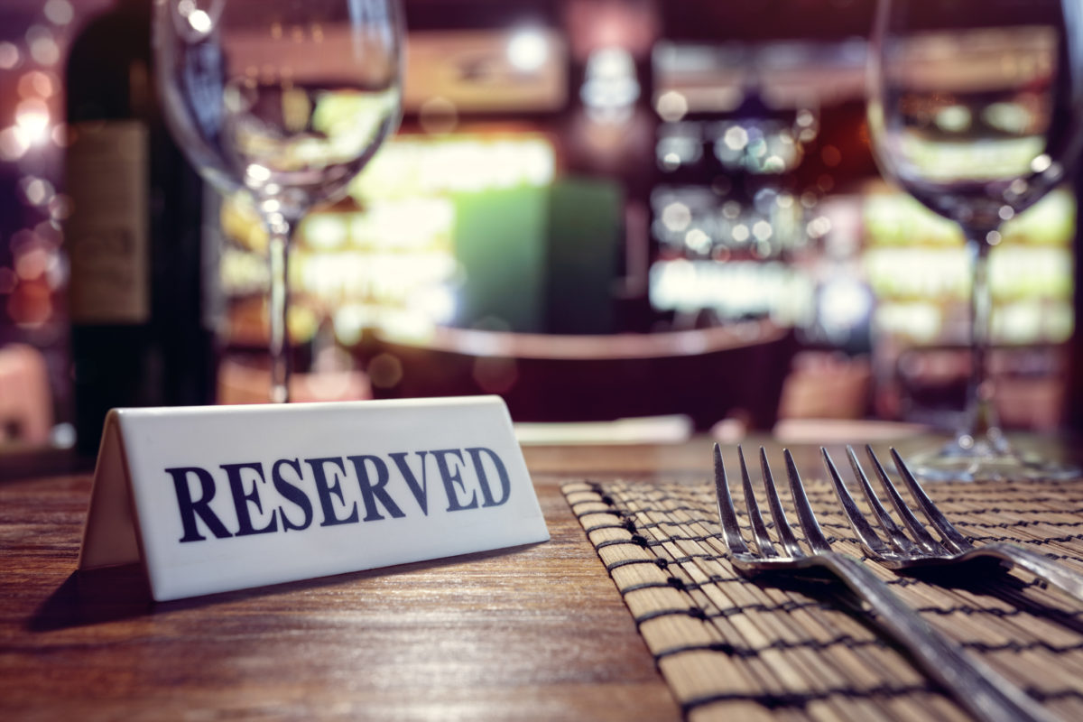 Restaurant reserved table sign with places setting and wine glasses ready for a party